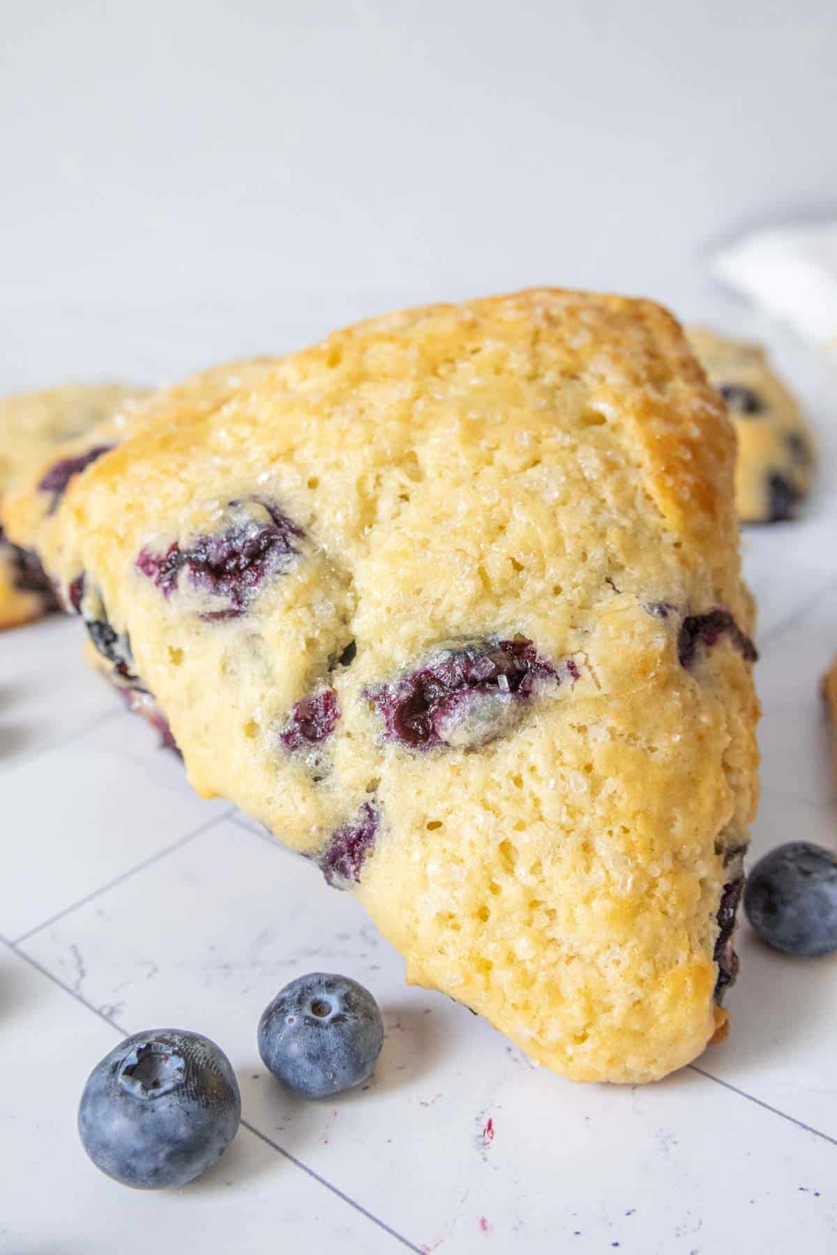 Close up of blueberry scone with blueberries next to it.