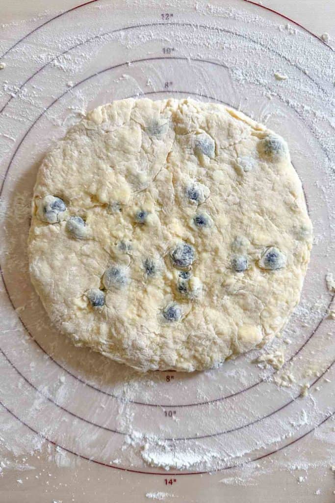 Blueberry scone dough on a floured pastry mat.