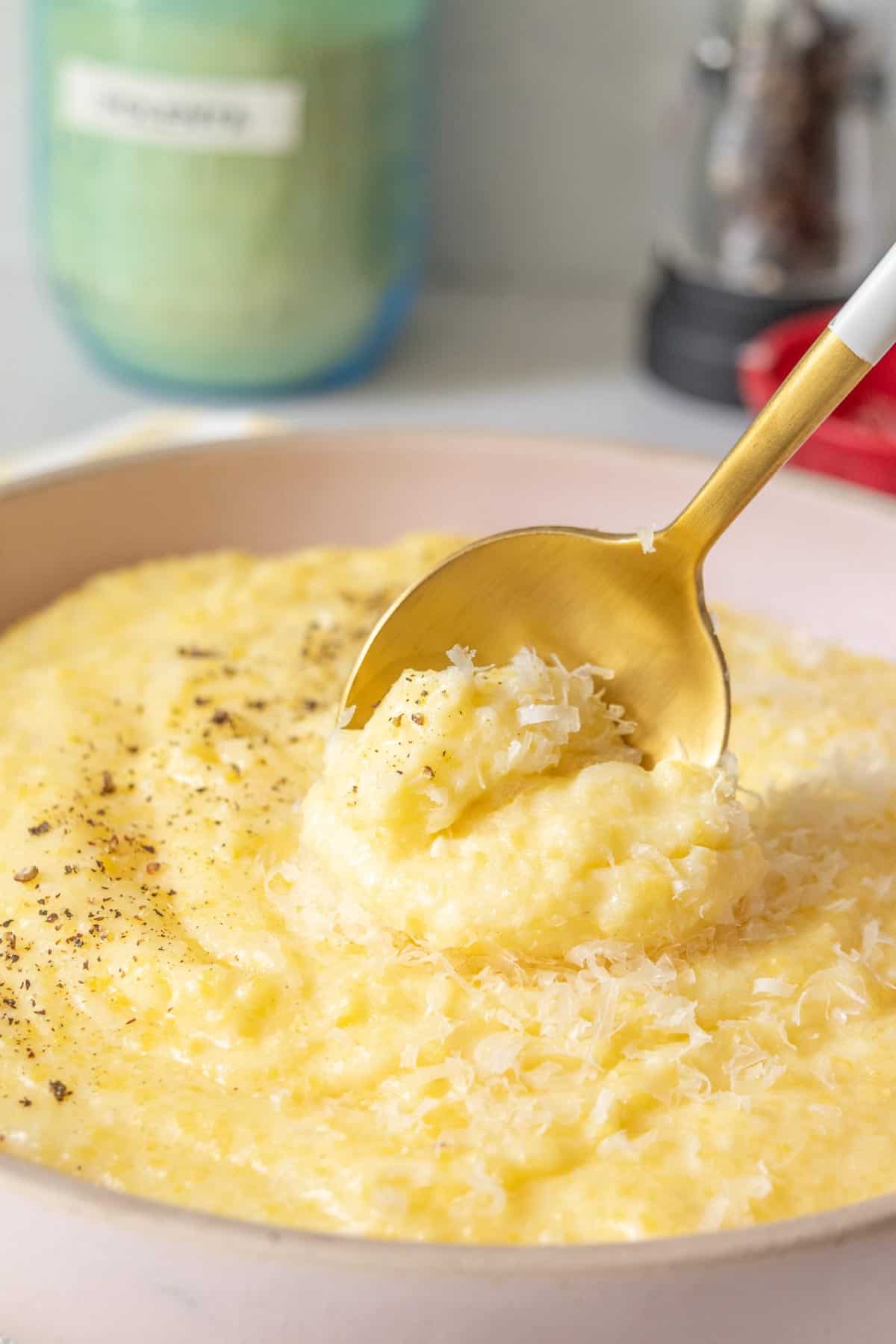 Bowl of cheesy polenta with a spoon stirring.