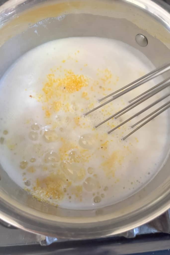Whisking polenta into boiling water and milk.