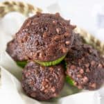 Chocolate zucchini muffins stacked in a basket.