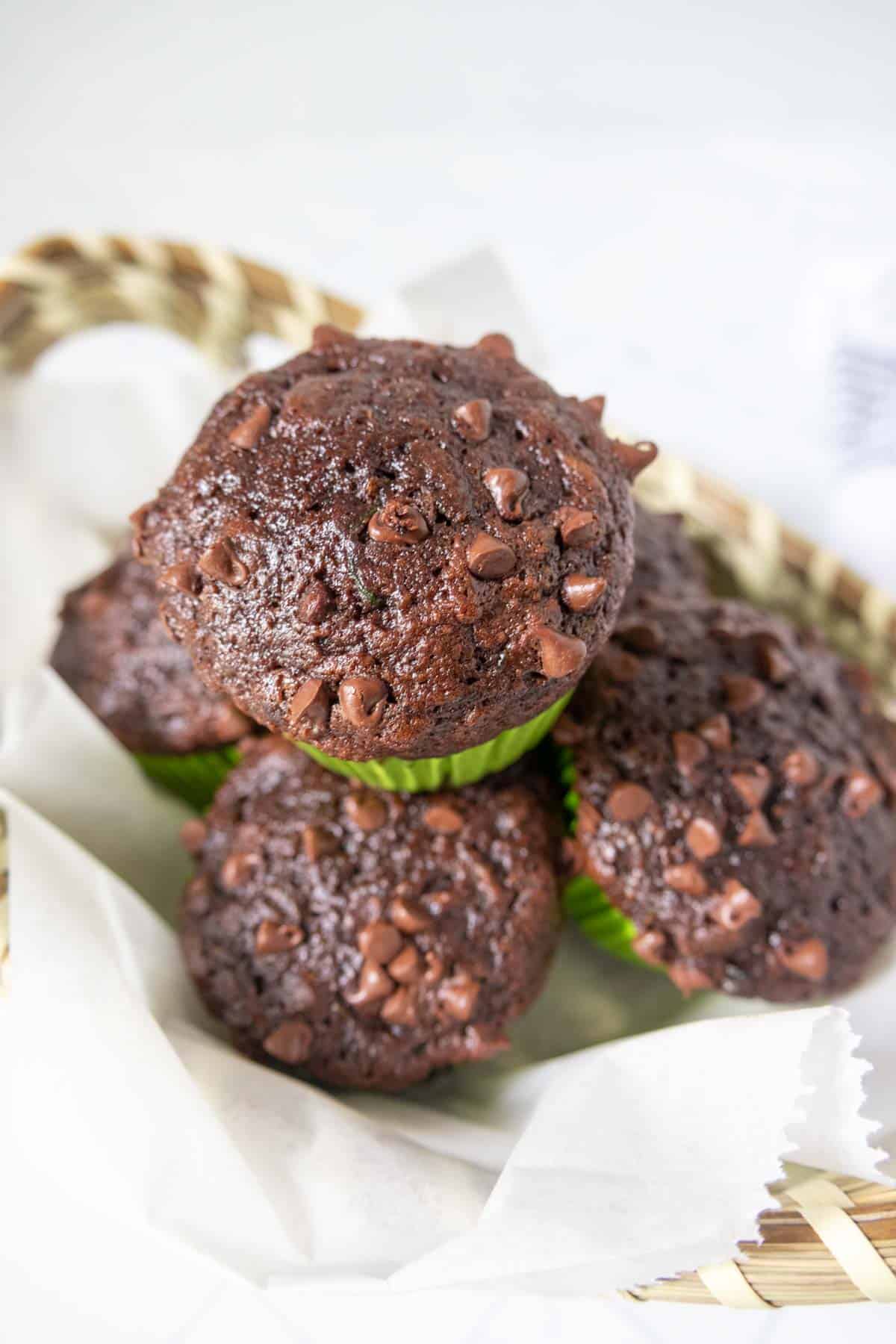 Chocolate zucchini muffins stacked in a basket.