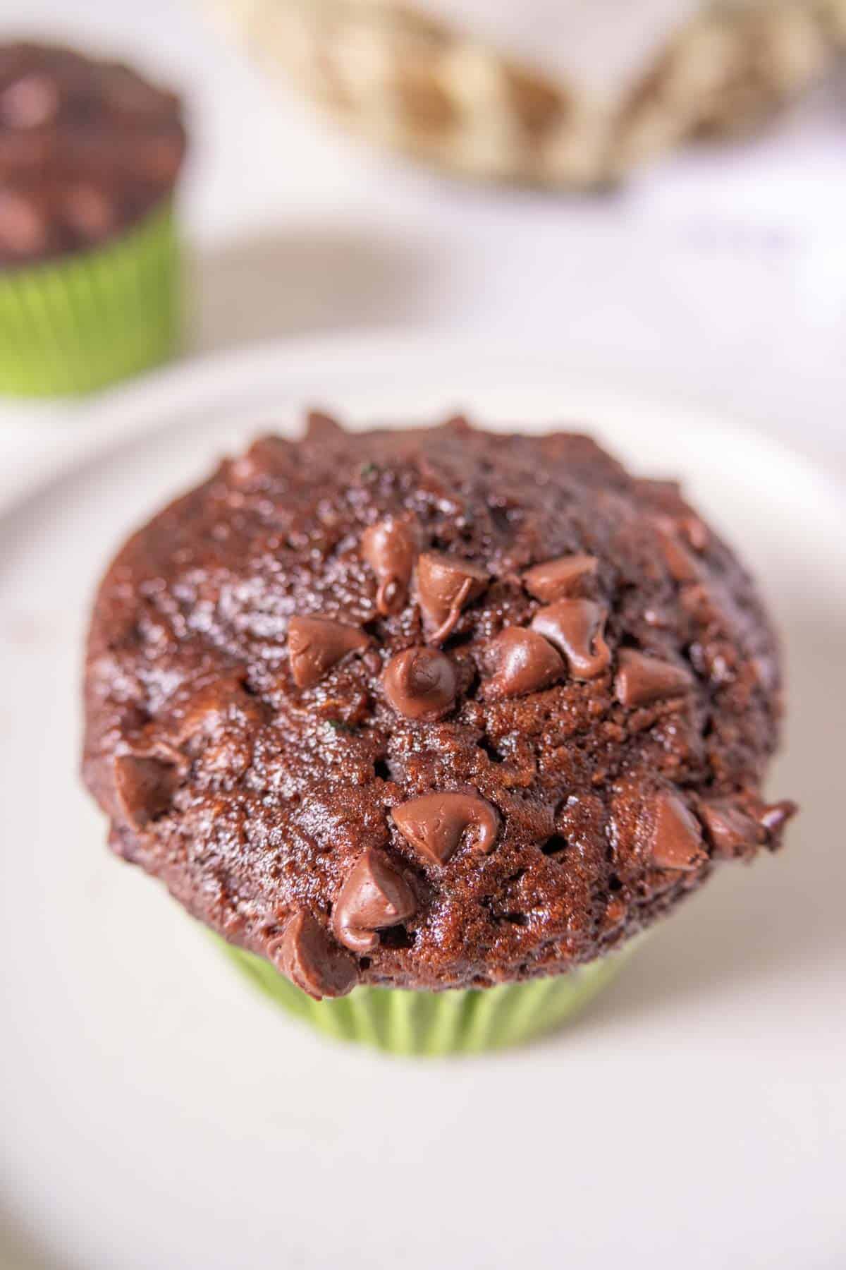 Close up of chocolate zucchini muffin showing chocolate chips on top.