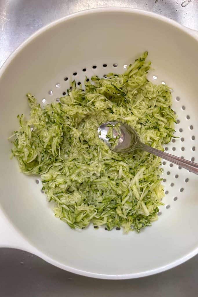 Shredded zucchini in a colander being drained.