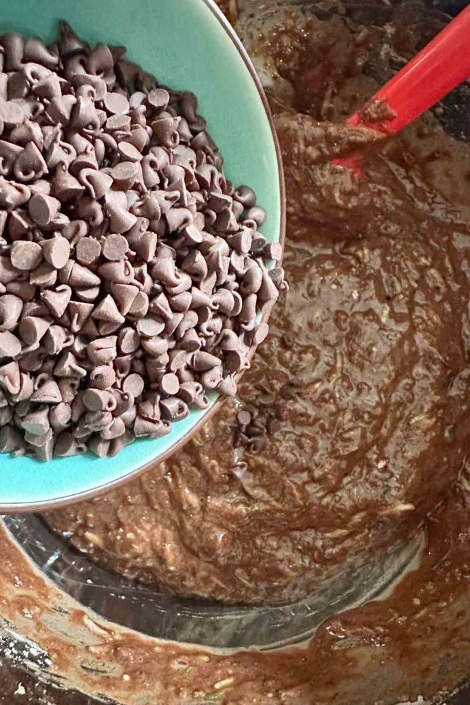 Adding mini chocolate chips to chocolate zucchini muffin batter.