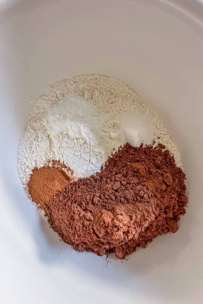 Dry ingredients for chocolate zucchini muffins in a white bowl.