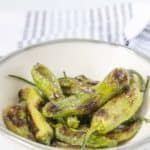 Gray bowl of grilled shishito peppers.