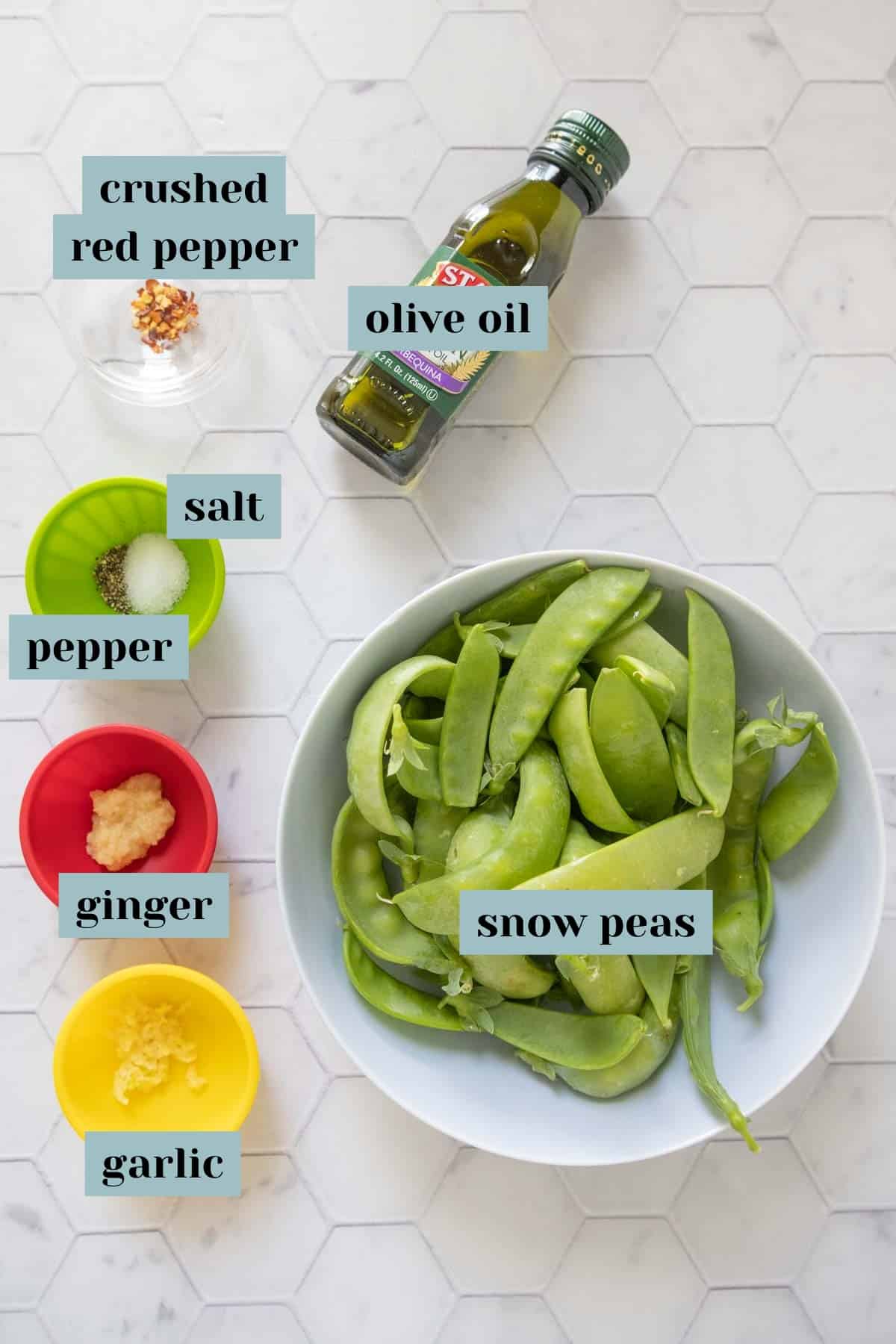 Ingredients for snow peas on a tile surface with labels.