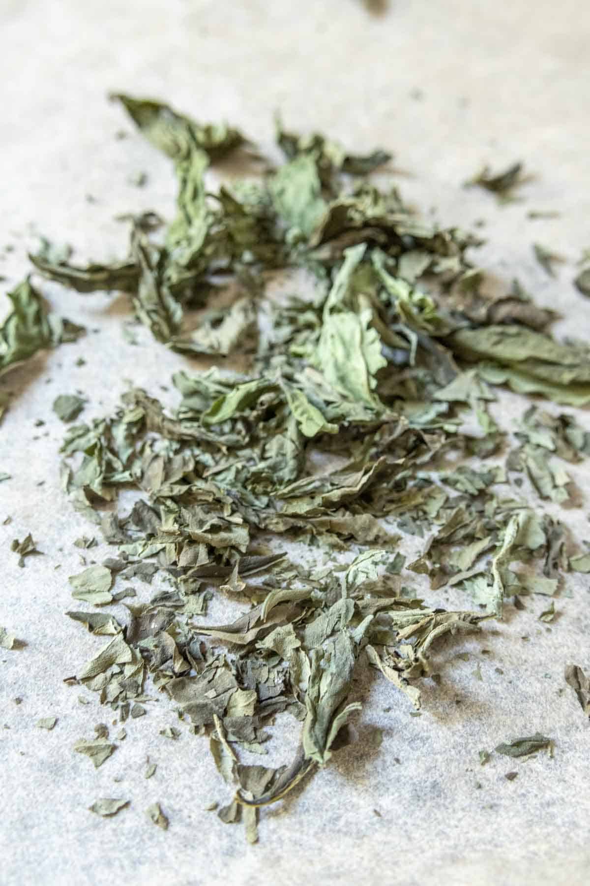 Crushed dried basil leaves on parchment paper.