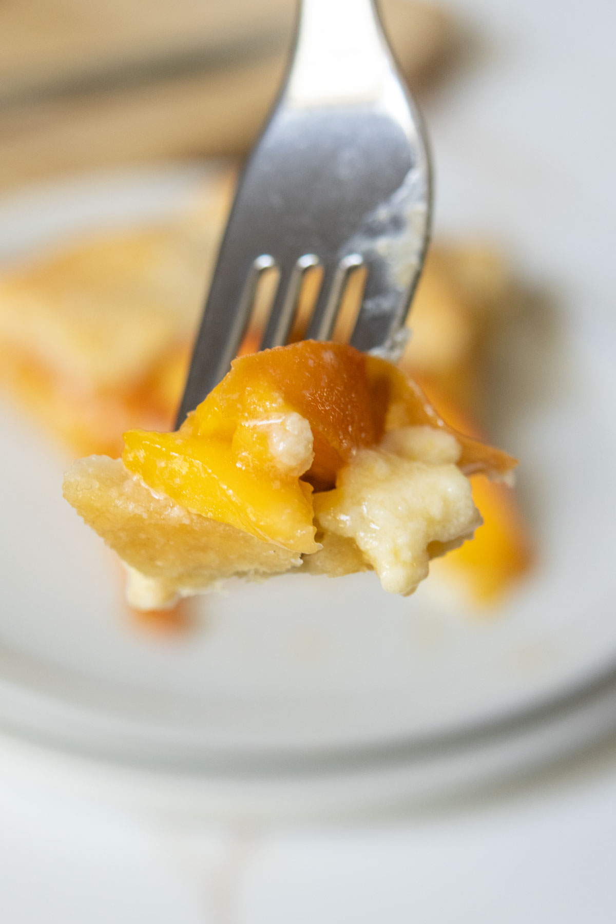 Fork holding up a bite of peach galette.