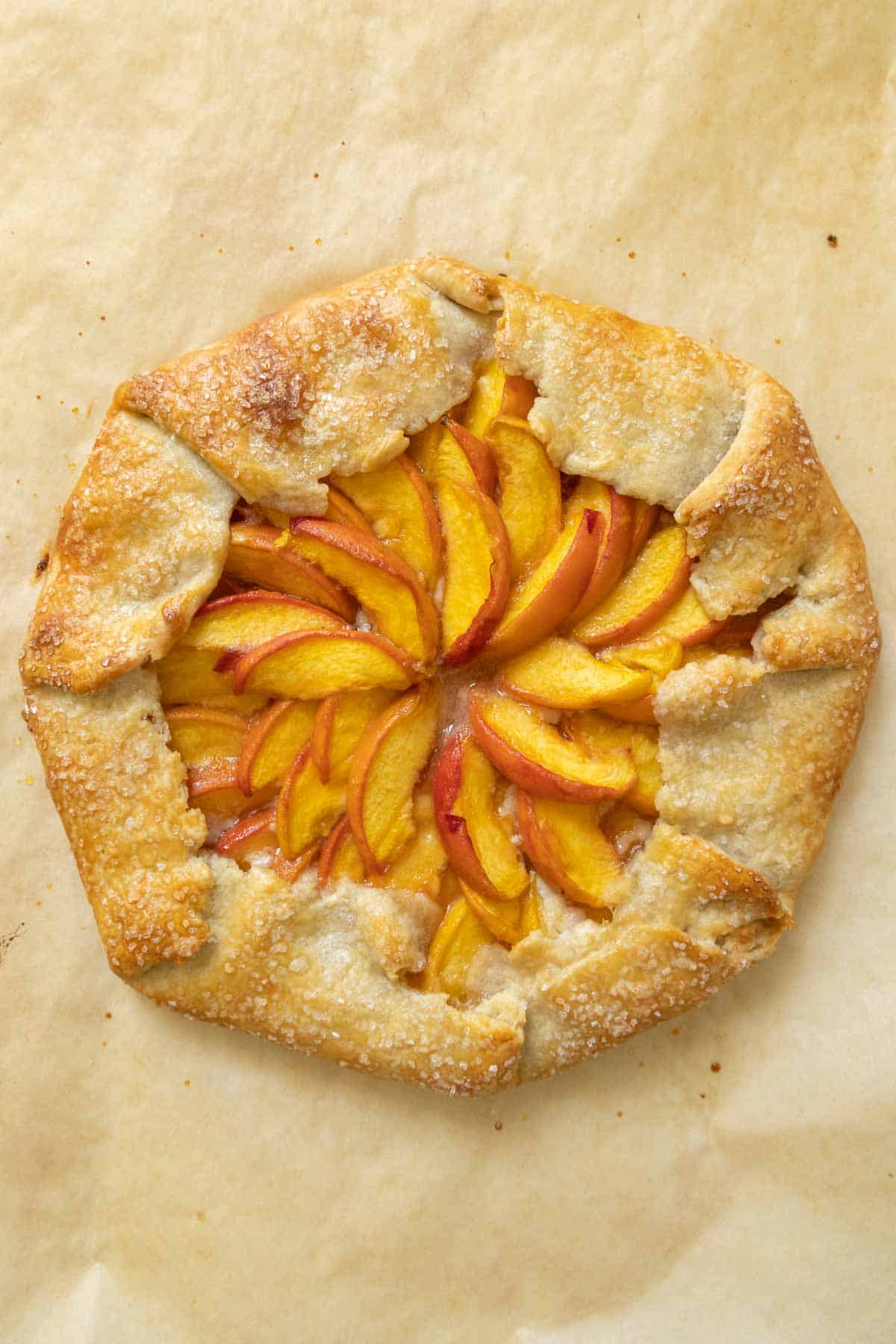 Overhead of baked peach galette on parchment paper.