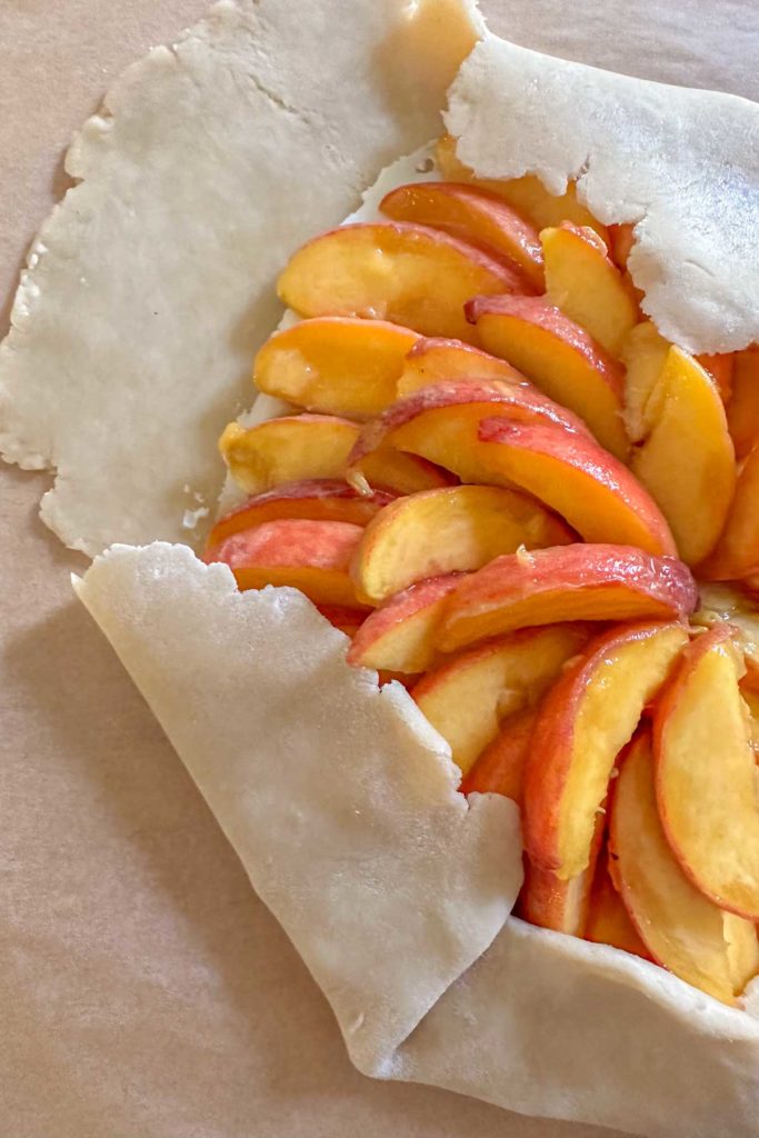 Folding over pie crust dough for peach galette.