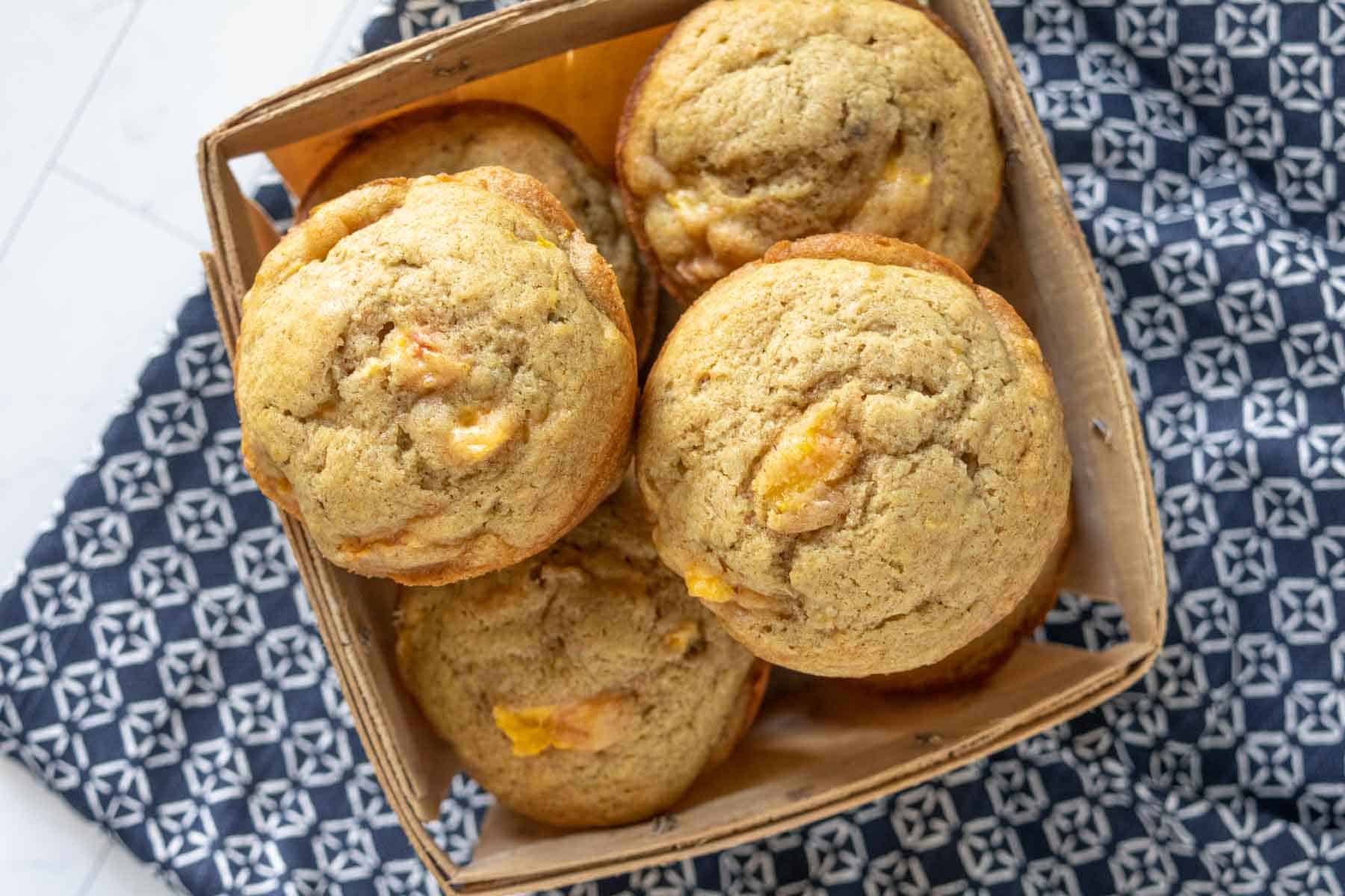 Overhead of peach muffins in a wood fruit basket.