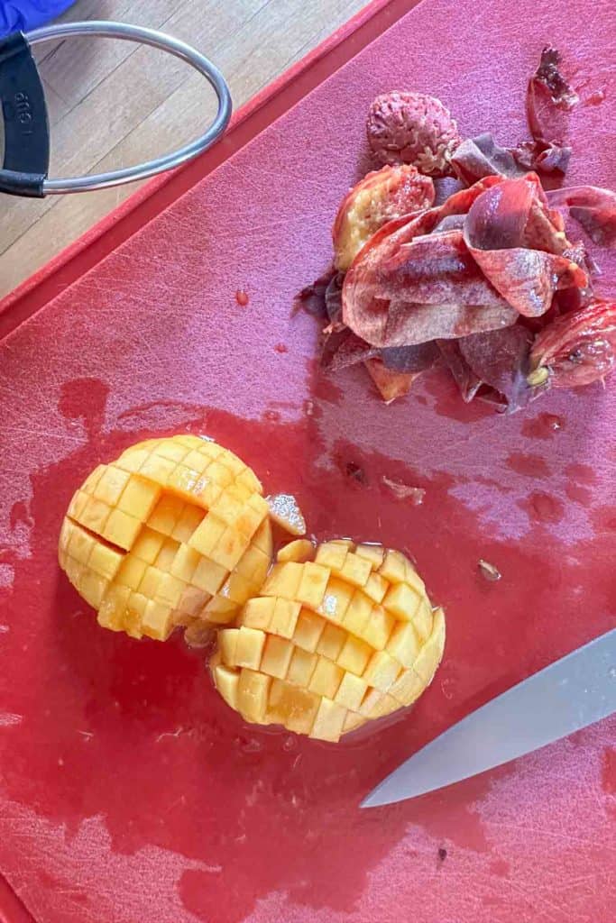 Diced peaches on red cutting board.