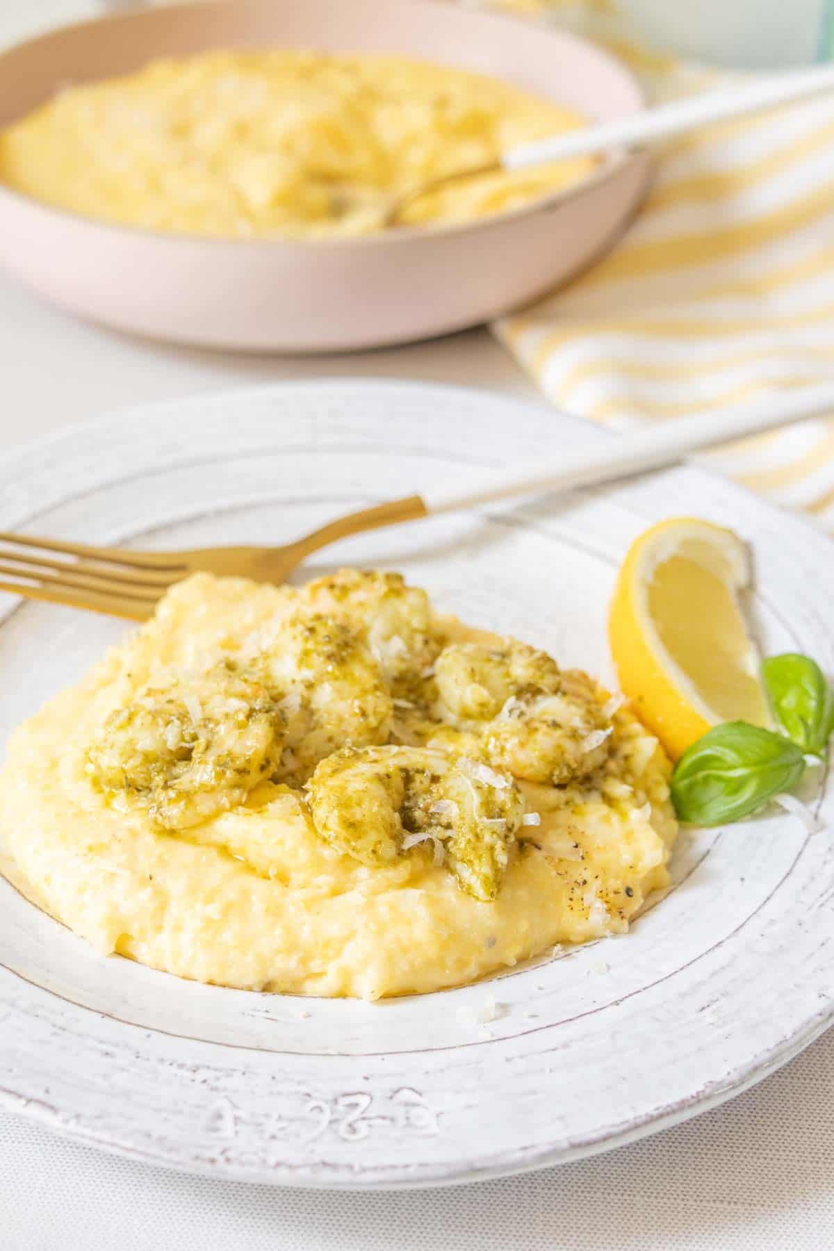 Plate of pesto shrimp on top of cheesy polenta.