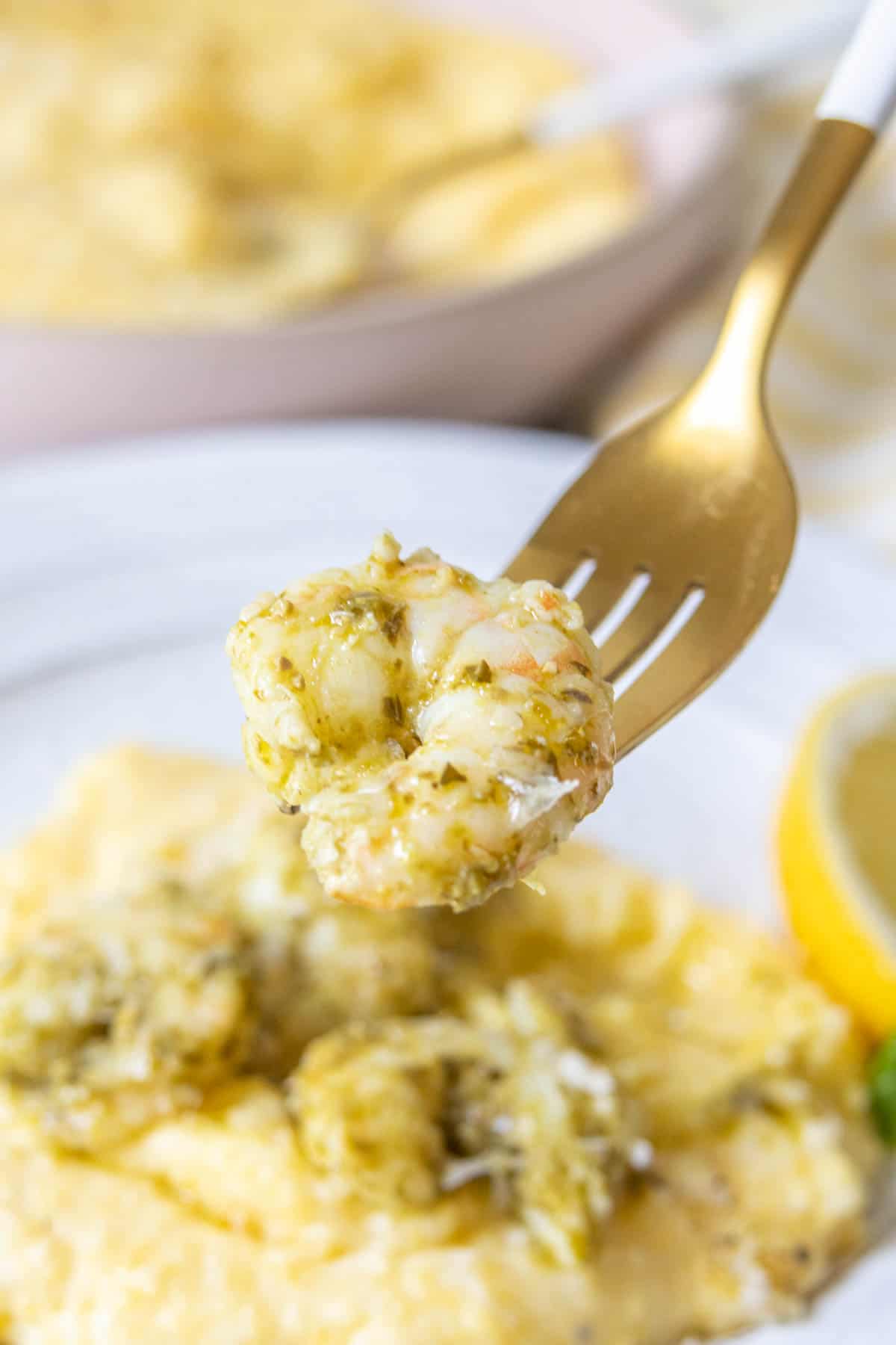 Fork holding up a piece of pesto shrimp.