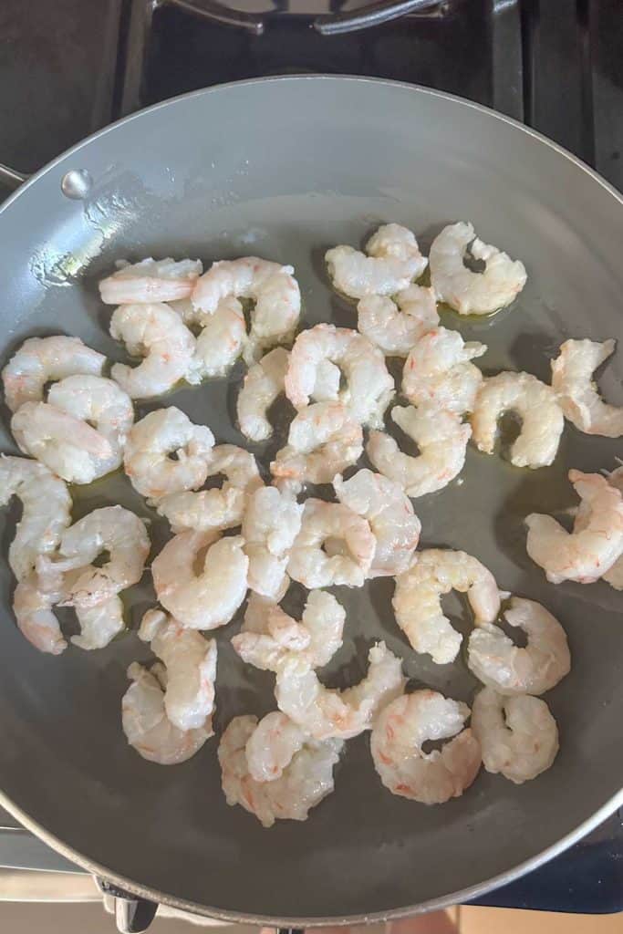 Sauteeing shrimp in a frying pan.