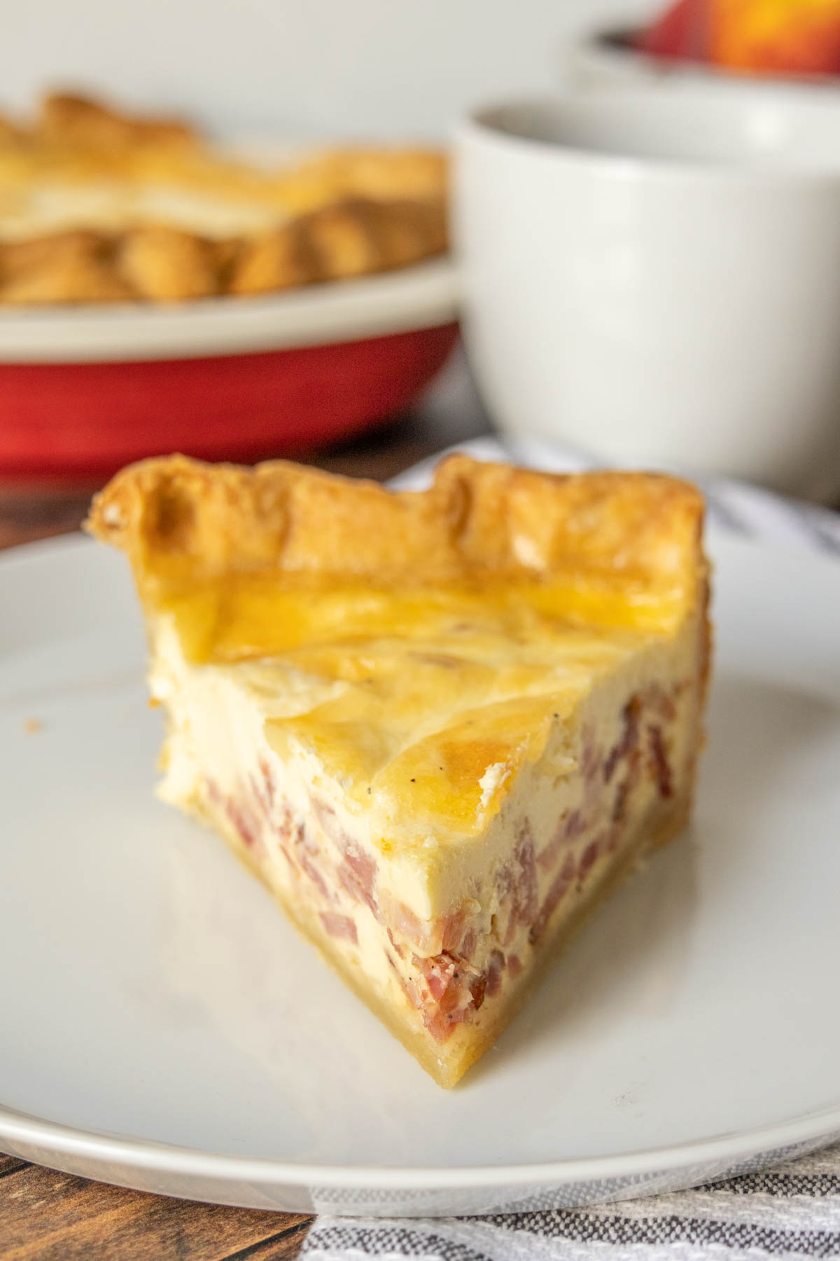 Slice of quiche lorraine on a plate from the front.