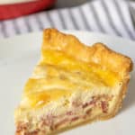 Slice of quiche lorraine on a white plate.