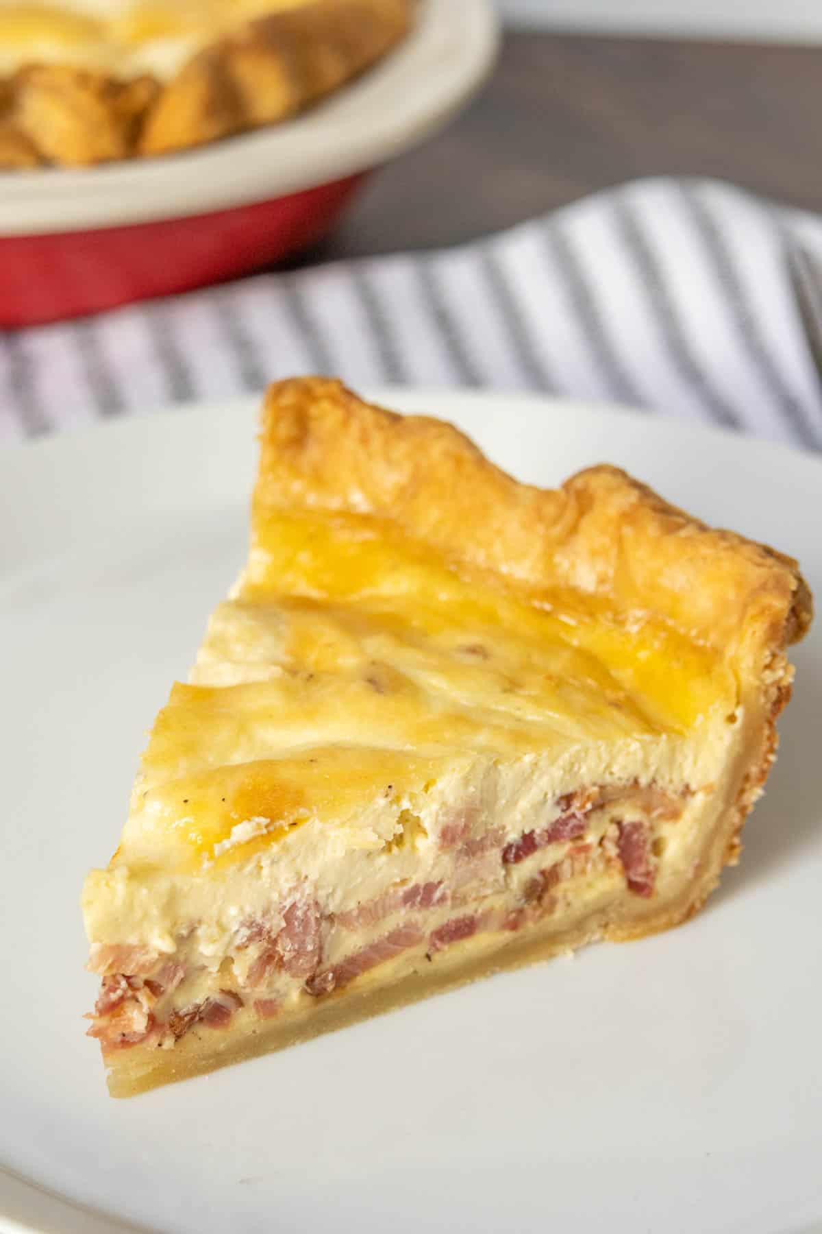 Slice of quiche lorraine on a white plate.