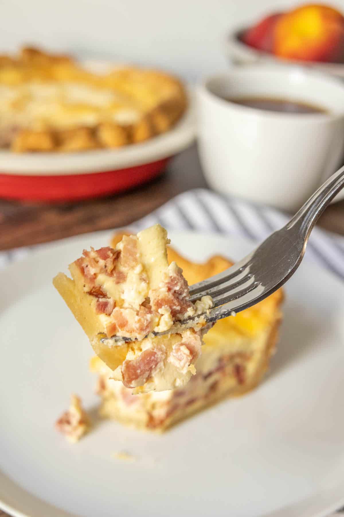 Fork holding up a bite of quiche lorraine.