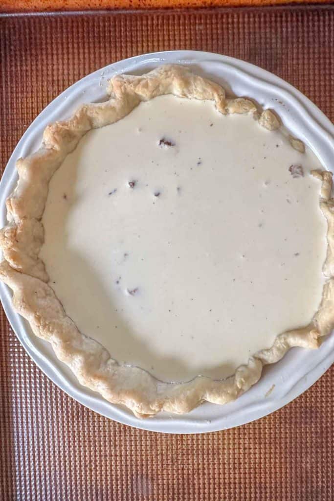 Unbaked quiche lorraine on a baking sheet.