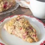 Red rimmed plate with a raspberry scone on top.