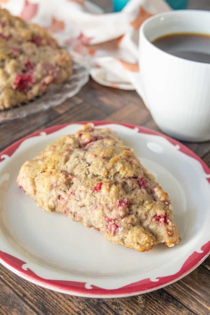 Red rimmed plate with a raspberry scone on top.