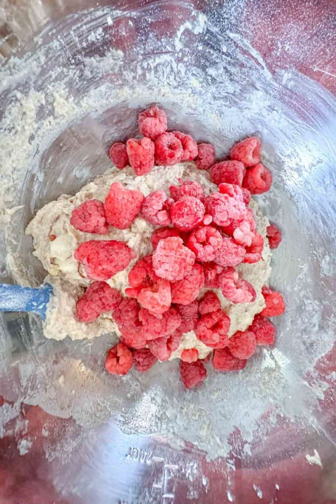 Raspberries being folded into scone dough in mixing bowl.