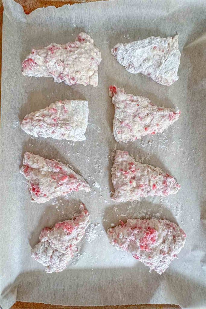 Unbaked raspberry scones on baking sheet.