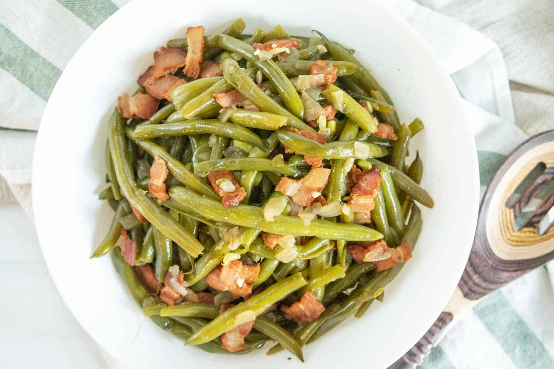 Southern green beans with bacon and onions in a white serving bowl.