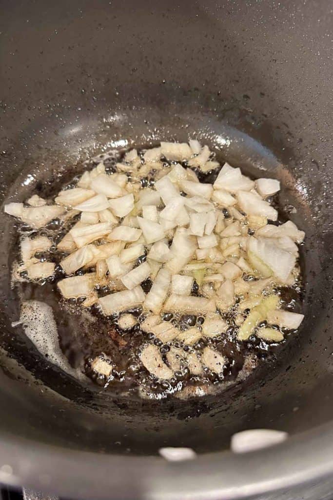 Onions cooking in bacon fat on the stove.