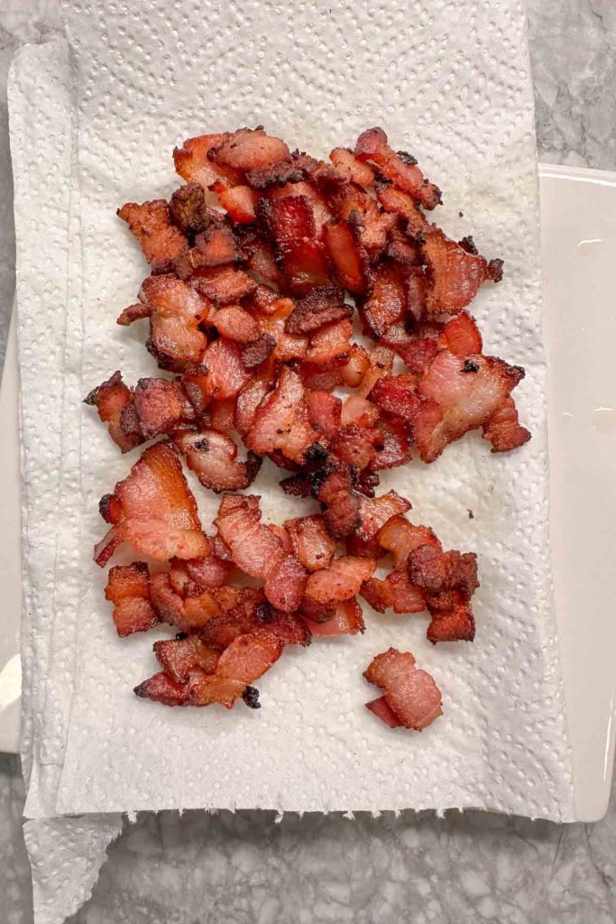 Crispy cooked bacon pieces on a paper towel.