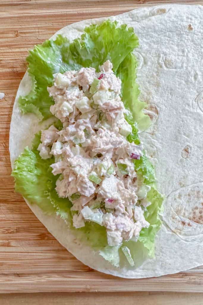 Tuna salad on lettuce on a tortilla before wrapping.