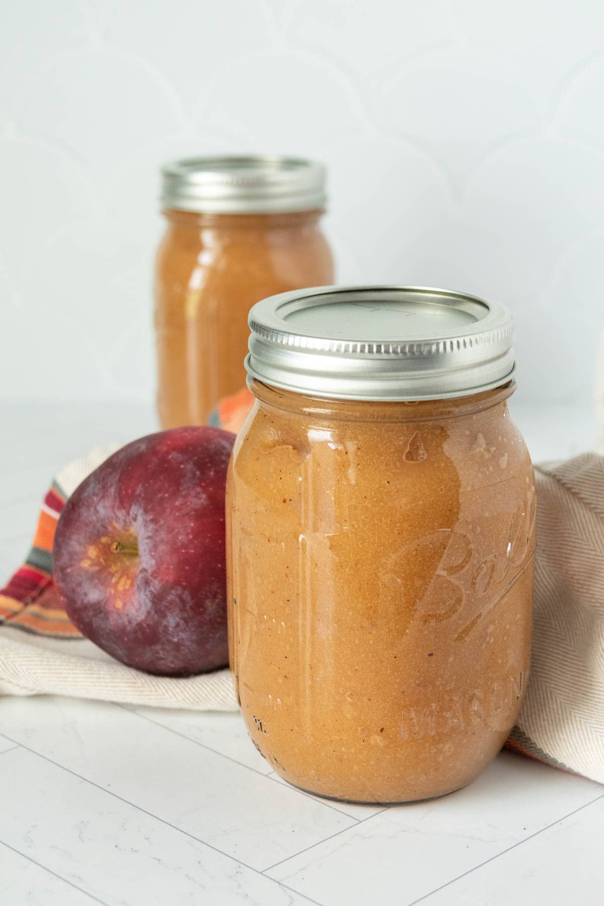 Two jars of apple butter on a table.