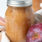 Apple butter in a jar next to an apple.