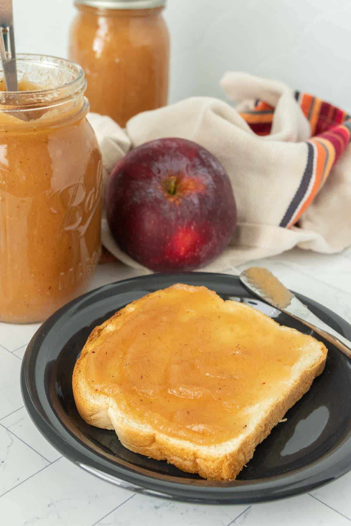 Apple butter on a plate next to a slice of bread.