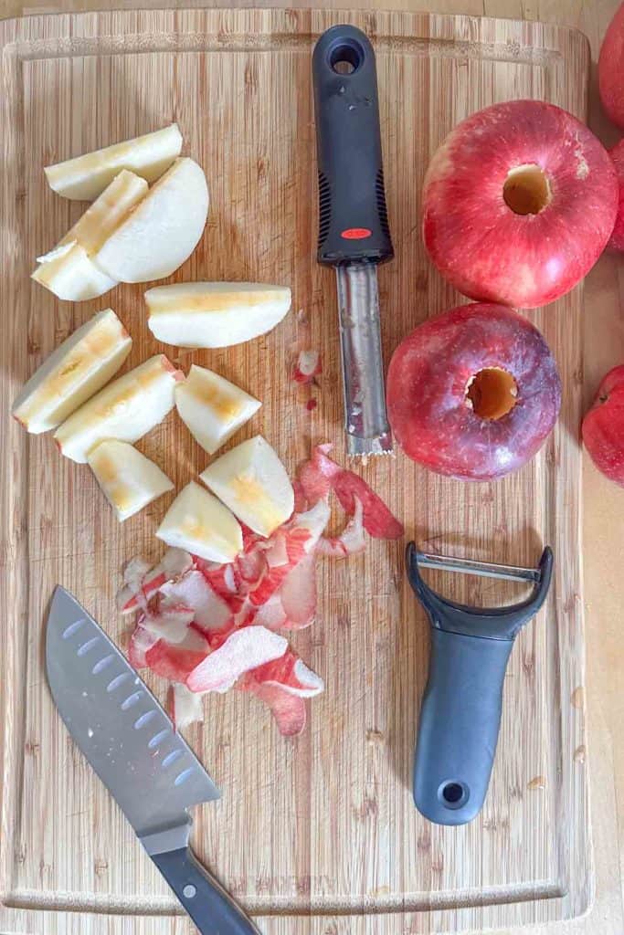 A cutting board with apples and a knife.
