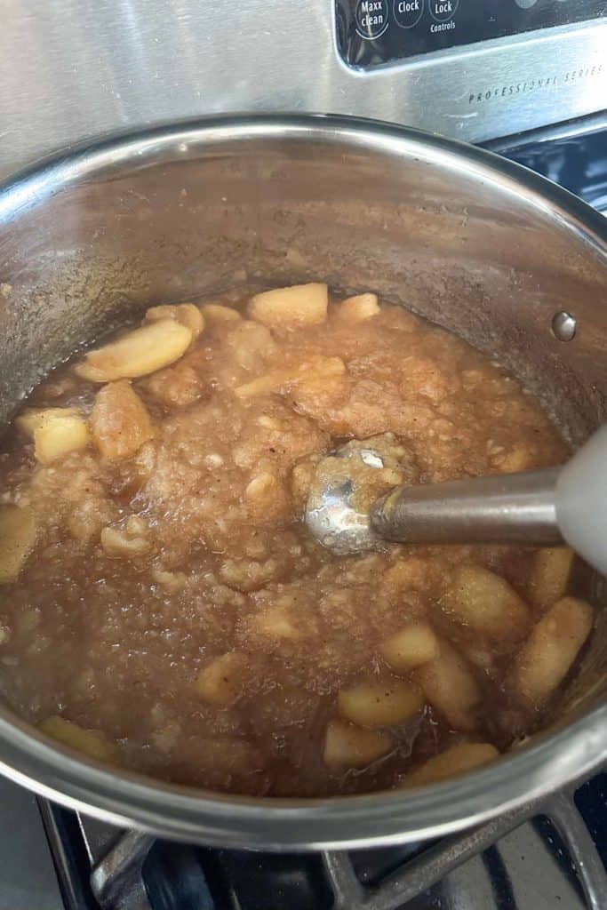 A pot with apples in it being cooked on a stove.