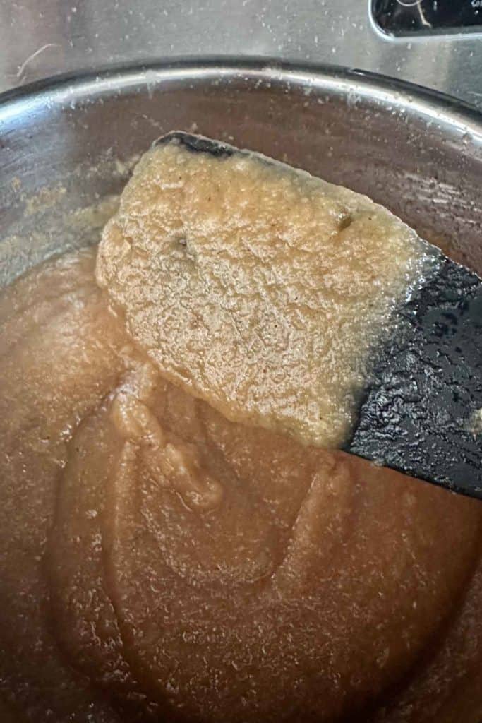 A spatula being used to stir apple butter in a pot.