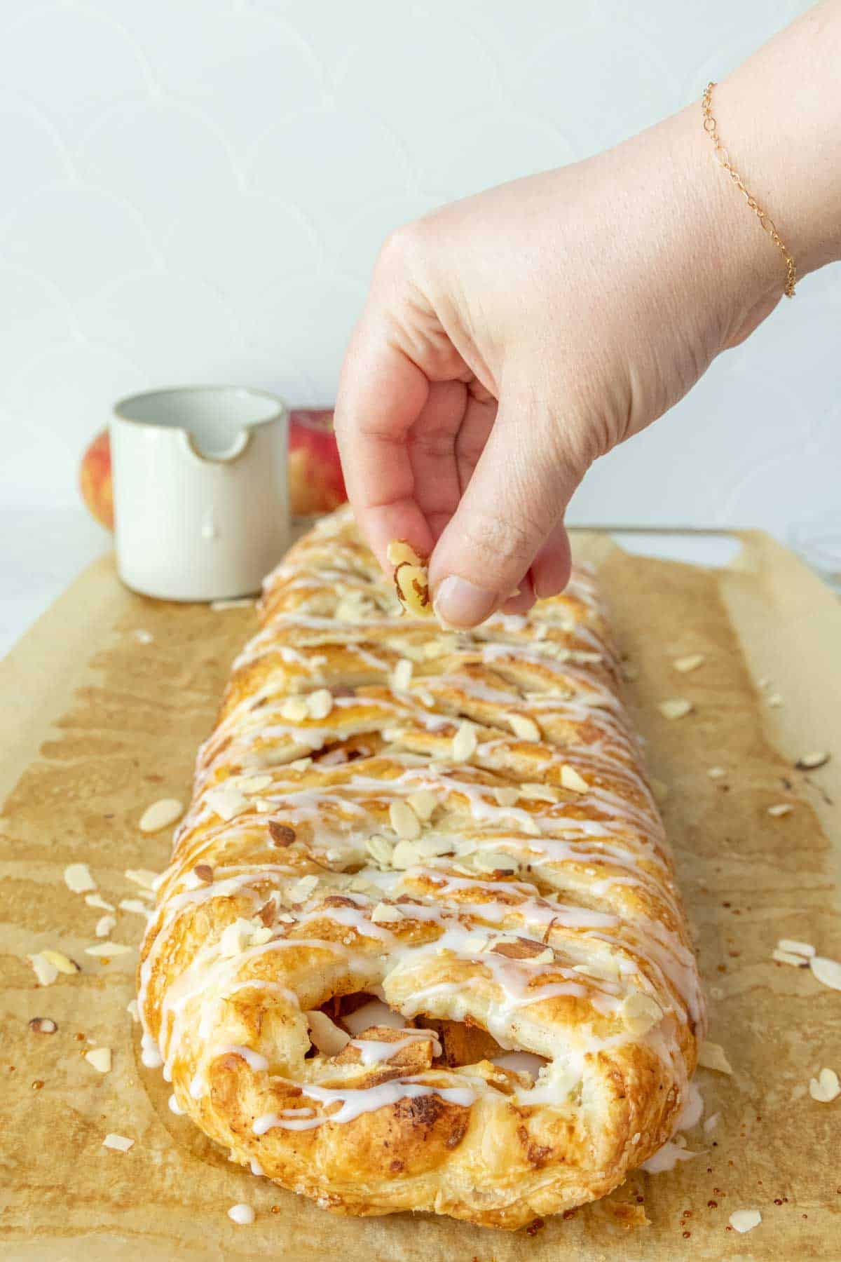 A person putting almonds on a pastry.