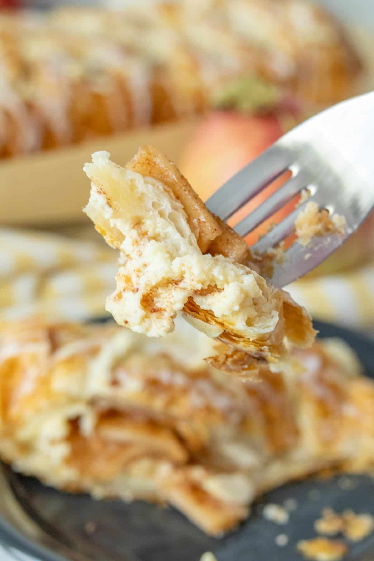 A fork is being used to pick up a piece of apple danish.
