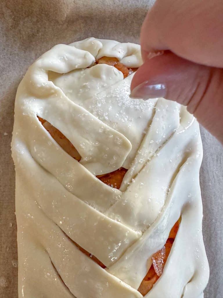 A person sprinkling sugar onto a pastry.