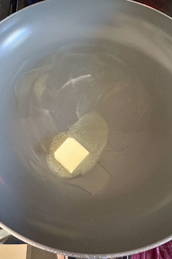 A frying pan with a piece of butter in it.