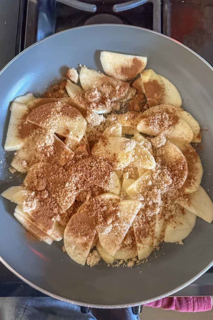 Apple slices in a pan with cinnamon and sugar.