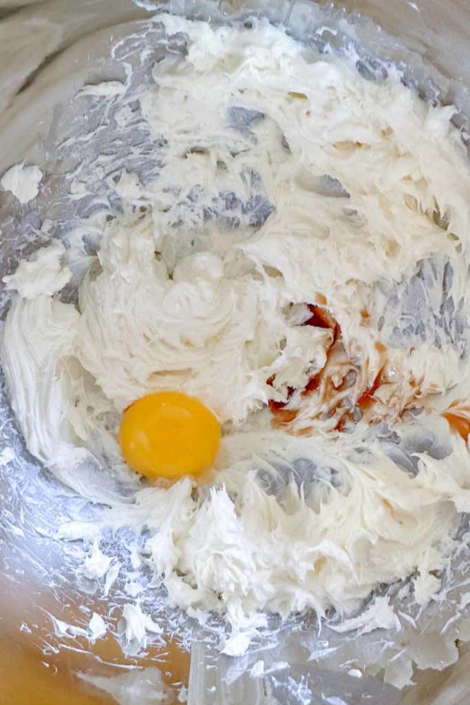 Whipped cream cheese, vanilla, and eggs in a mixing bowl.