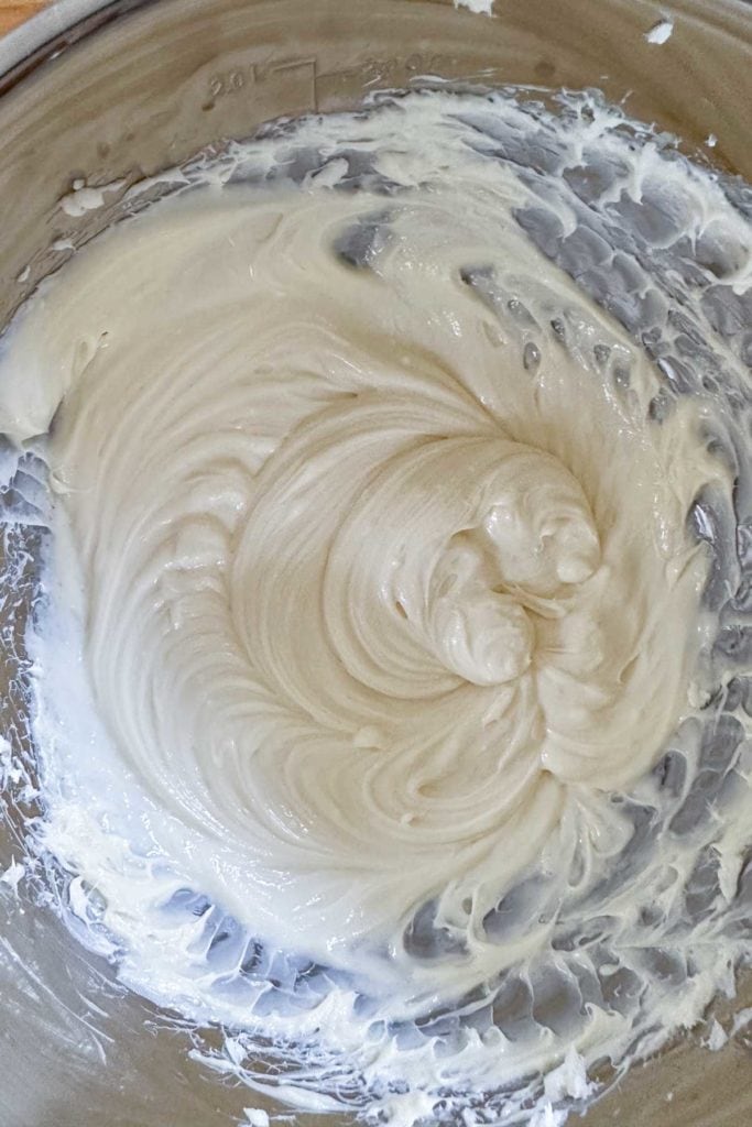 Whipped cream cheese filling in a bowl on top of a wooden table.