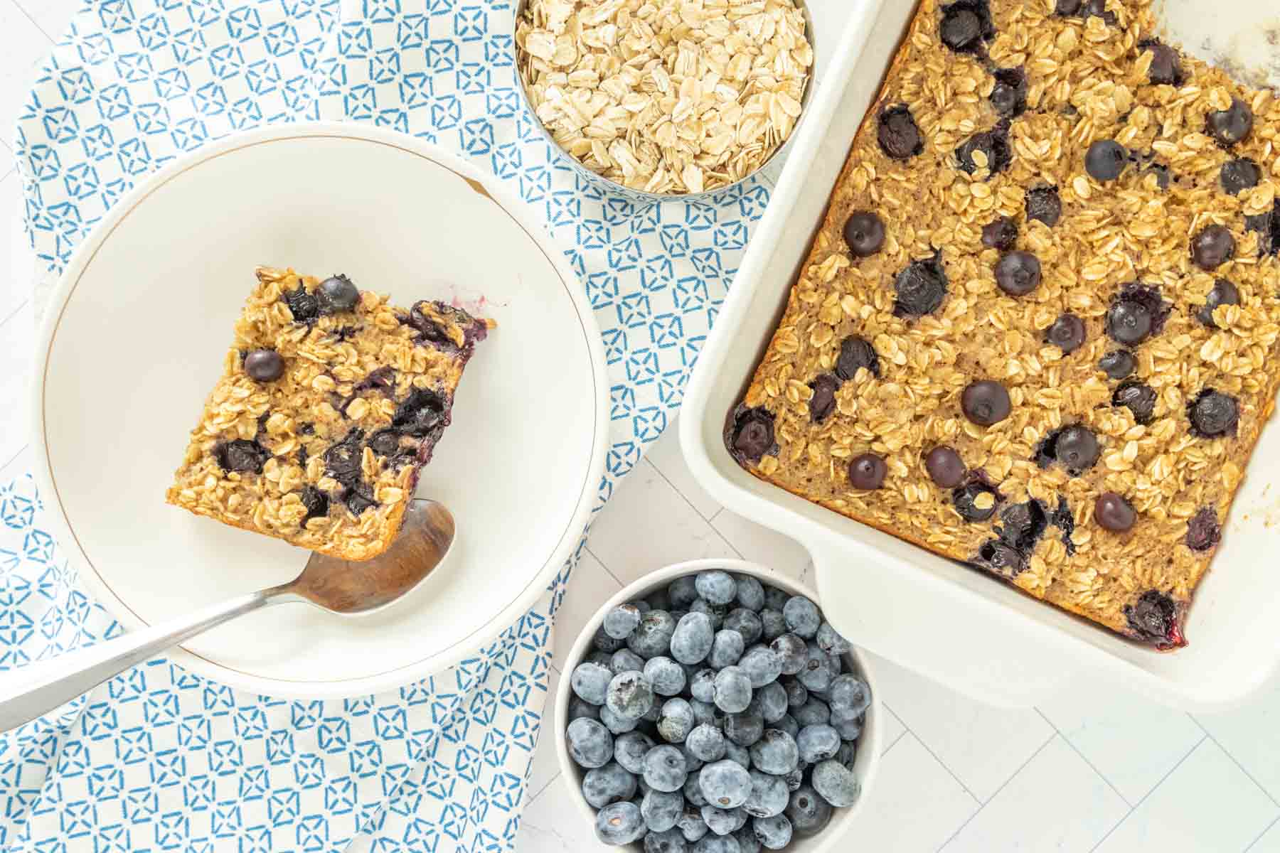 Blueberry baked oatmeal in a white dish with blueberries.