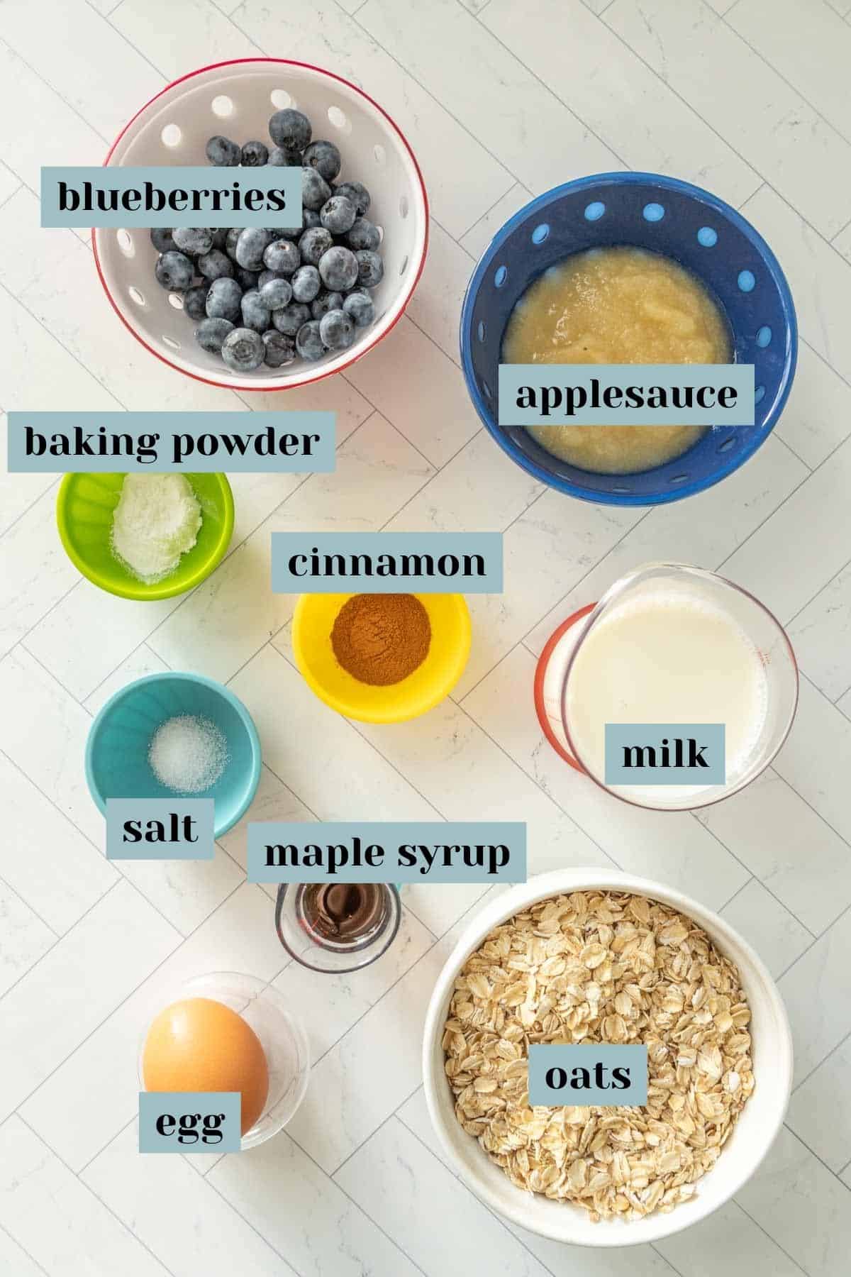 The ingredients for blueberry oatmeal are shown on a white marble countertop.