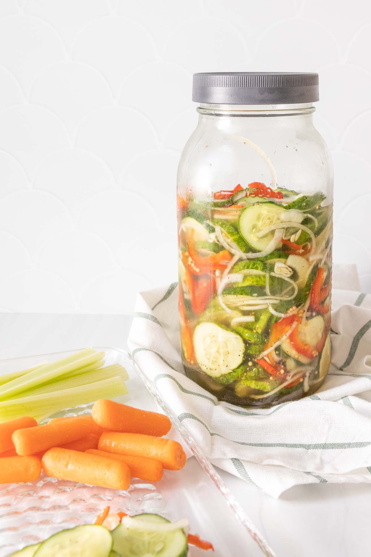 A jar of pickled vegetables with carrots and cucumbers.